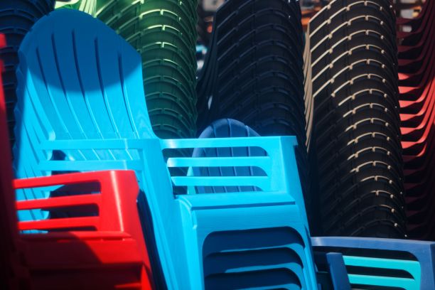 在一个阳光明媚的日子里，蓝色的塑料椅子堆在一起图片下载