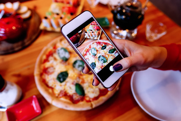 女孩用智能手机给披萨拍照。披萨的照片图片下载