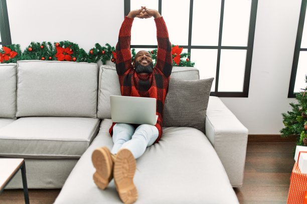 年轻的非裔美国人使用笔记本电脑坐在圣诞节装饰在家里图片下载
