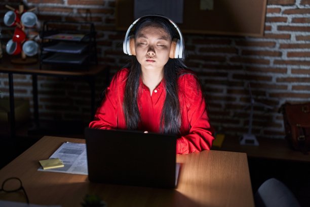 年轻的中国女商务工作者在办公室听音乐放松图片下载