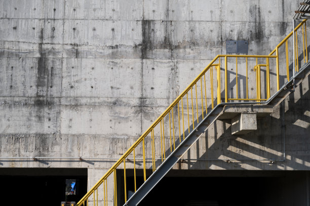 金属楼梯，混凝土墙上的黄色栏杆图片下载