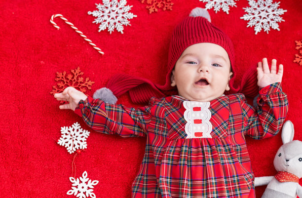 可爱的白人婴儿躺在地板上，圣诞装饰在孤立的红色背景图片下载