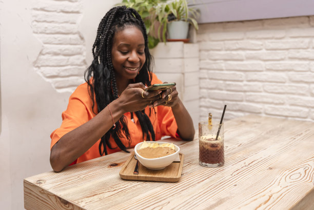 一个美丽的非裔美国女人坐在酒吧里拍着巴西莓碗和花生酱的照片图片下载