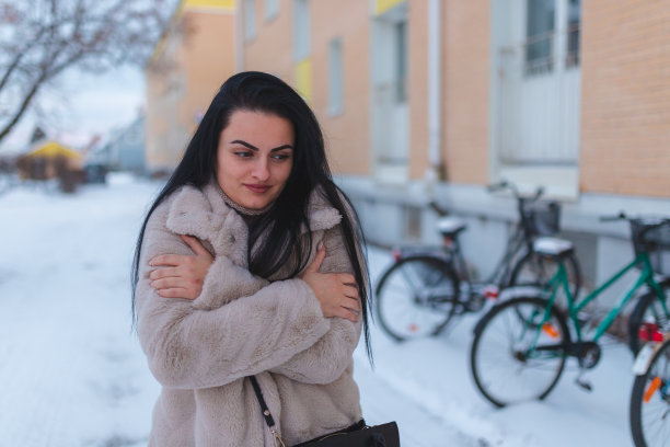 年轻的黑头发女人冻在雪地里图片下载