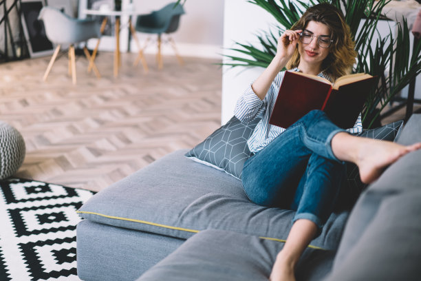 年轻女子在沙发上看书休息图片下载