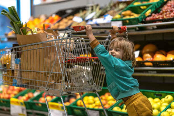 一位母亲带着孩子在卖新鲜蔬菜的商店里图片下载