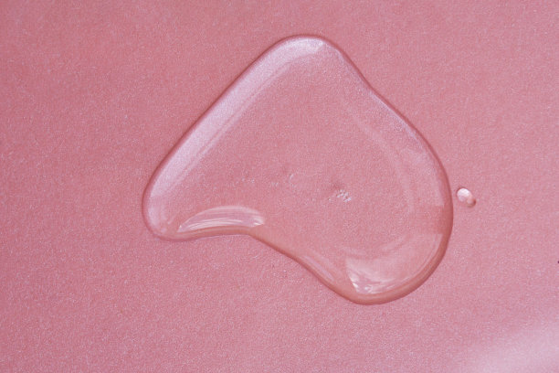 粉红色背景上的一滴化妆品或香水。图片下载