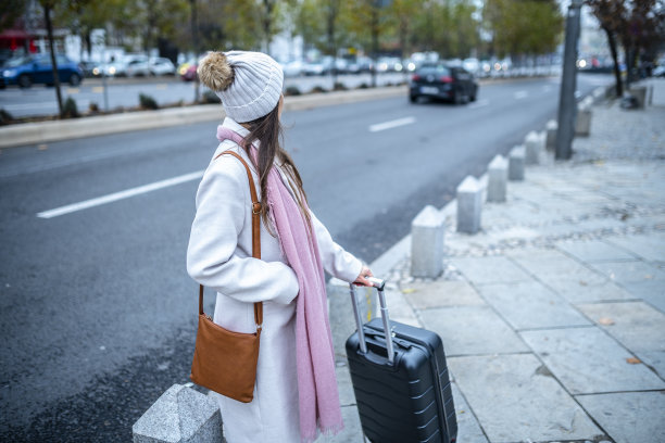 城市的生活方式。一个带着行李箱的女人在城里度假。图片下载