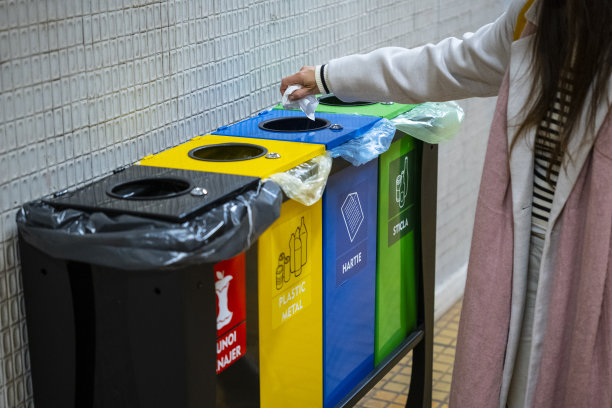 女孩把垃圾扔进回收箱。城市的可持续发展。图片下载
