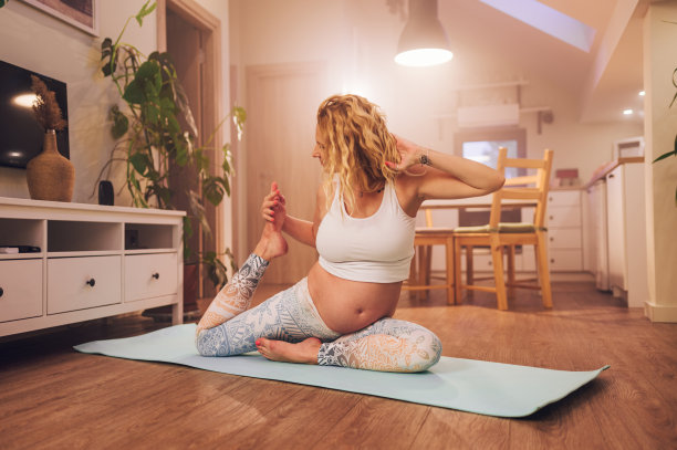 年轻的孕妇在家里的运动垫上做产前瑜伽图片下载