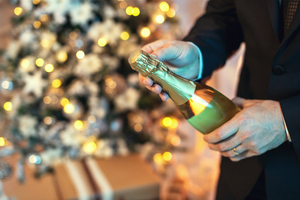 一个西装男子打开一瓶香槟的特写镜头图片下载