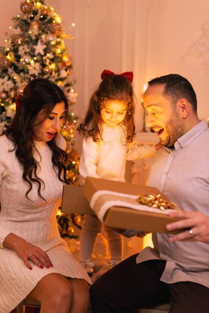 幸福的一家打开礼盒，背景是圣诞树和壁炉图片下载