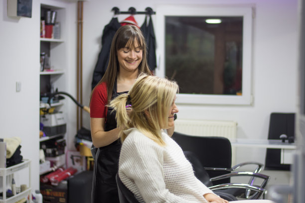 理发师在发廊里吹干一个成熟的金发女人的头发图片下载