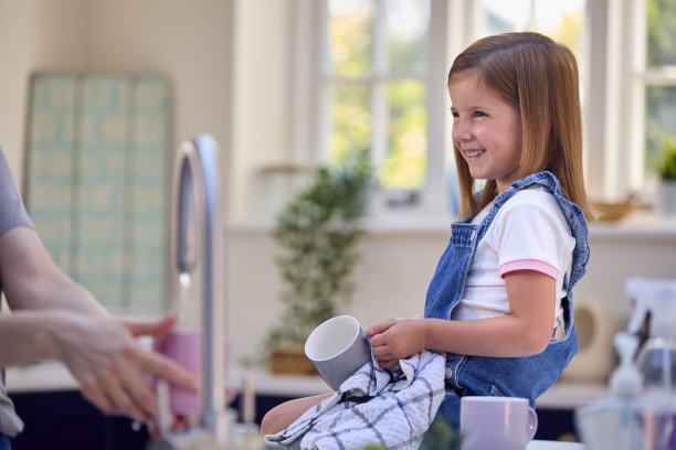 家庭特写，女儿帮助年长的母亲在家里的厨房洗碗图片下载