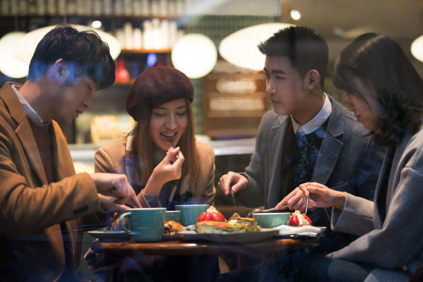 两对年轻的东亚夫妇在冬天坐在咖啡馆里吃甜点图片下载