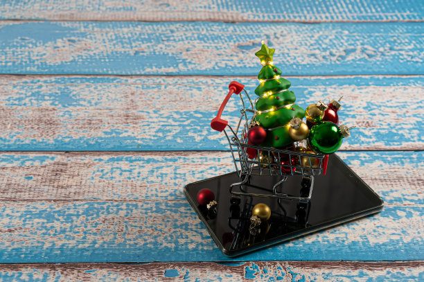 商店手推车上的圣诞球和树与花环的平板电脑。简单的背景。图片下载
