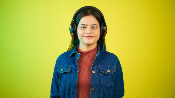 年轻女子听音乐与无线耳机在她的头上，快乐的少女享受音乐孤立的色彩背景图片下载