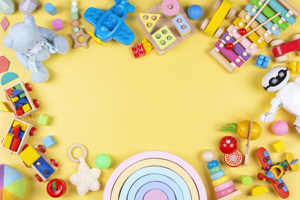 色彩丰富的教育木制塑料和蓬松的儿童玩具在柔和的黄色背景。俯视图，平面布局图片下载