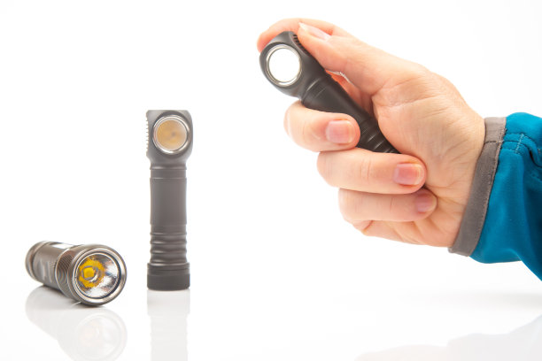 一只手拿着手电筒，背景是白色背景上的其他手电筒。露营和家庭用品。图片下载