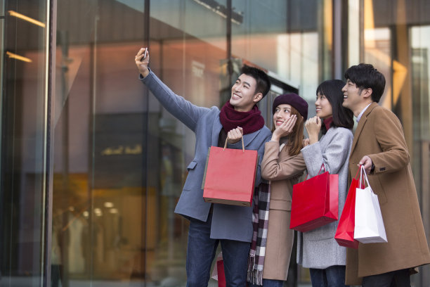 年轻的东亚夫妇在冬季繁忙的户外购物街购物时自拍-库存照片图片下载