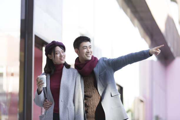 年轻的东亚夫妇在冬季繁忙的户外购物街买咖啡-库存照片图片下载