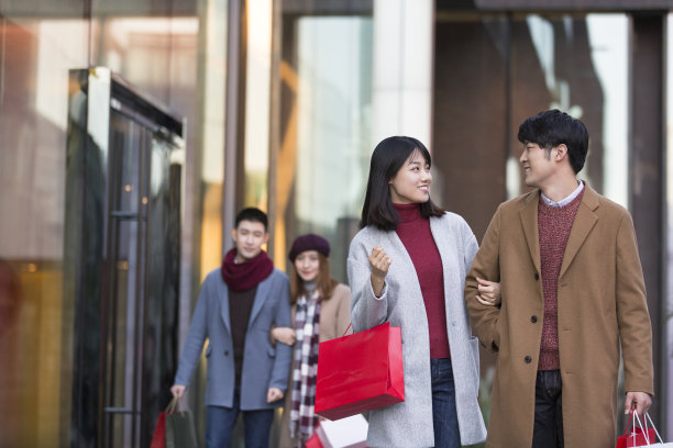 冬季情人节，年轻的东亚情侣在繁忙的户外购物街购物图片下载