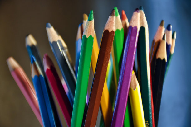 蓝色笔记本和各种彩色铅笔和刷子放在一张模糊背景的木桌上图片下载