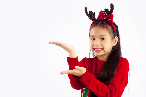 小亚洲孩子在红色运动衫圣诞主题服装摆姿势在白色背景。图片下载