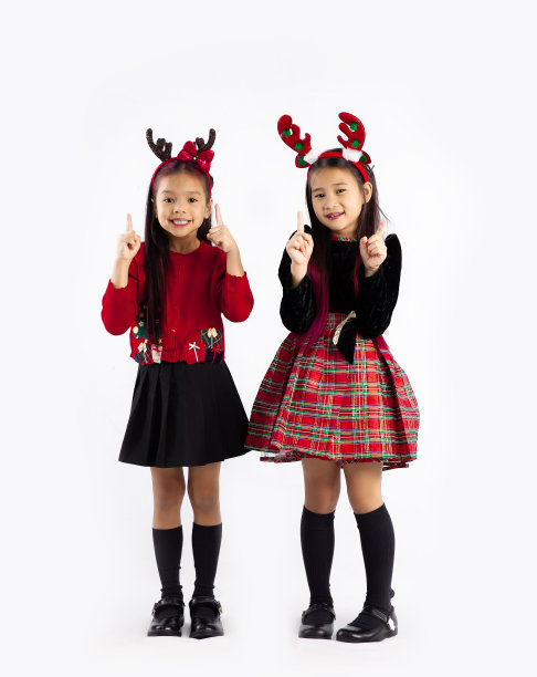 可爱的亚洲孩子在圣诞主题服装站和手指在白色背景。圣诞快乐。图片下载