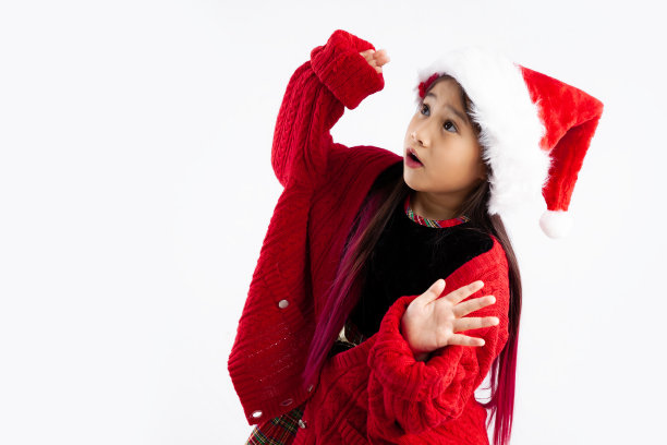 惊讶的亚洲女孩在红色毛衣圣诞老人帽子摆出惊讶的脸在白色背景。图片下载