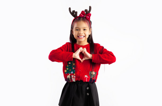 小亚洲女孩孩子在红色运动衫圣诞主题服装摆姿势在白色背景。圣诞快乐。图片下载