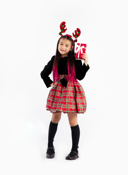 圣诞快乐，可爱的亚洲小孩女孩在黑色毛衣，驯鹿角头带圣诞主题服装手持红色礼物盒全长白色背景。图片下载