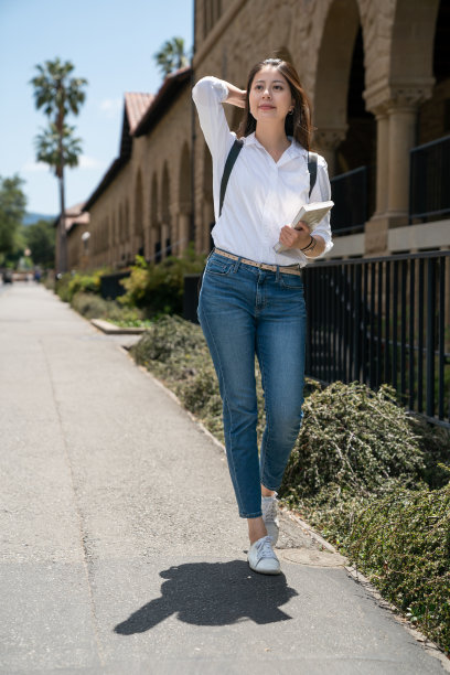 美国加州一所大学，一个满脸笑容的亚裔中国交换生，背着课本，梳着头发，在去上课的路上享受着阳光和微风图片下载