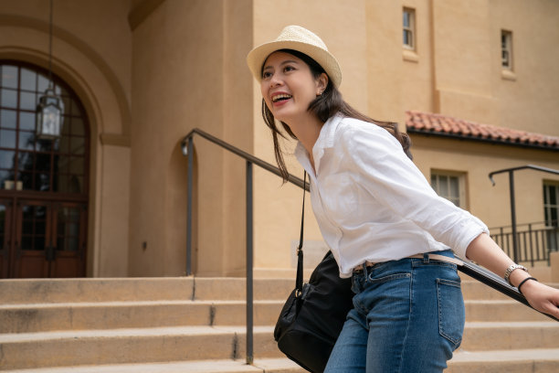 快乐的亚洲台湾女游客享受美丽的大学校园在楼梯附近的老建筑拱门入口门在美国加州大学图片下载