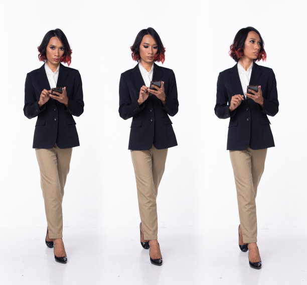 全长20多岁的亚洲女性穿着正式的商务礼服，西装外套，高跟鞋。黑色短卷发的女性走着开心的笑着拿着智能手机，走着向前，在白色的背景下左右孤立图片下载