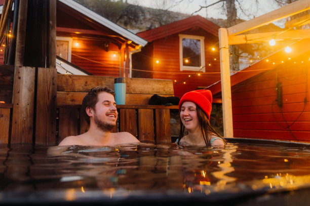 快乐的女人和男人放松在热水浴缸与风景优美的山景峡湾在冬天在挪威图片下载