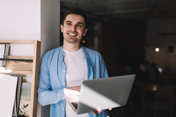 愉快的人与笔记本电脑站在墙附近图片下载