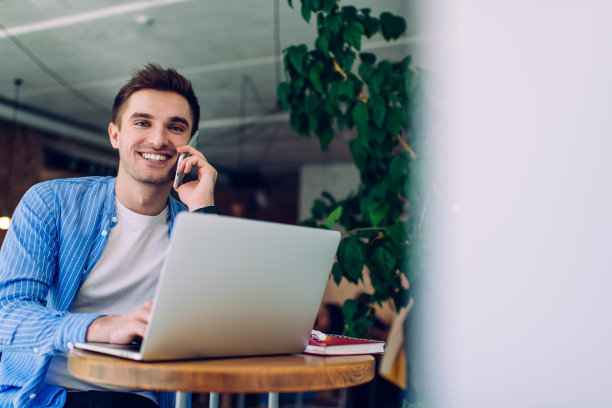 男性远程员工用智能手机聊天，用笔记本电脑打字图片下载