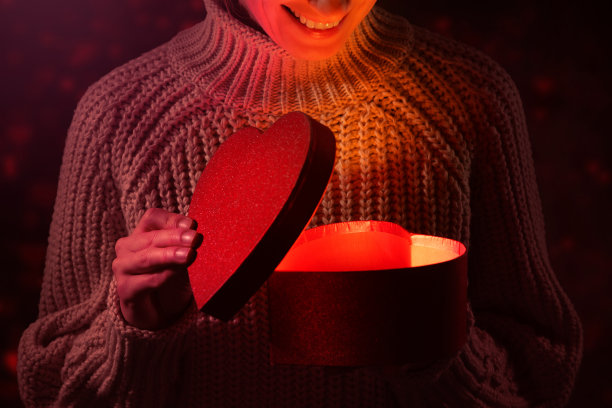 女人打开一个心形礼品盒。浪漫纪念日或情人节礼物图片下载