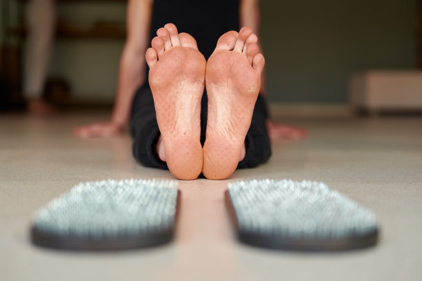 人的脚站在sadhu板(瑜伽板)。男子在室内练完瑜伽后坐在瑜伽室的地板上图片下载
