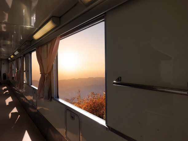 火车内部有人行道，外面有日落山景。图片下载