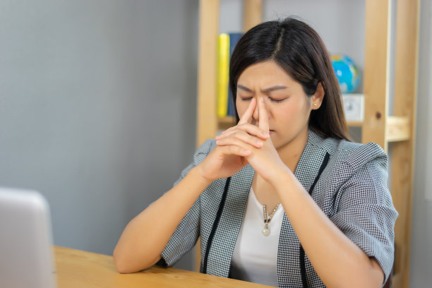 年轻的亚洲女性坐在笔记本电脑前，困了，累了，过度劳累，懒得工作。迷人的女商人在家里办公室打哈欠放松或无聊的工作后在电脑上图片下载