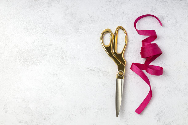 俯视图洋红色丝带和金色剪刀在白色表面。礼品包装概念，仪式开幕图片下载