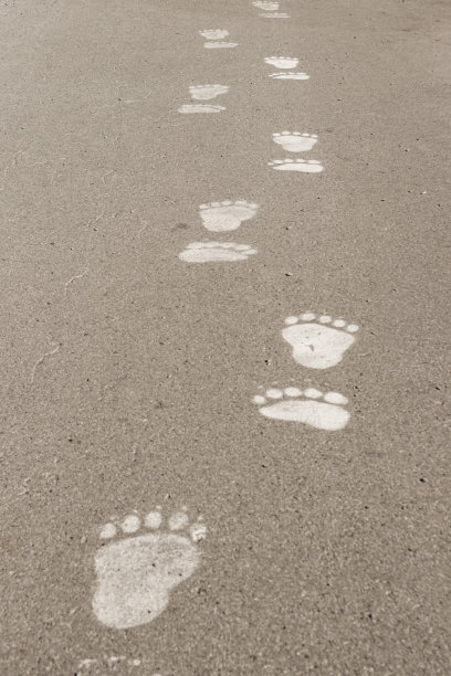 在砾石铺就的道路上，用白色粉刷的脚步引领前方图片下载