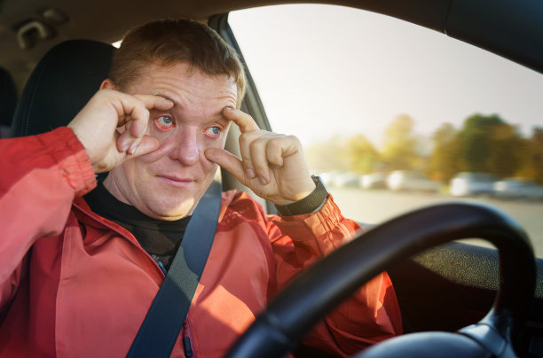 一位疲惫的司机在开车时用手指捂着眼皮，防止它们合上图片下载