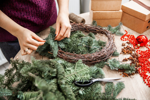 在她的工作室里，一位女装饰师正在用冷杉树枝做一个花环图片下载