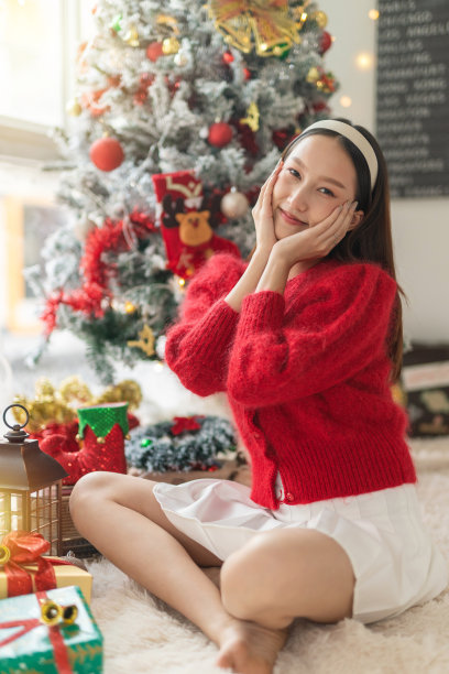 年轻美丽友好的亚洲女性女士，红色长袖毛衣衬衫和可爱的发带摆出不同的样子，在房间里装饰得很漂亮的圣诞树图片下载