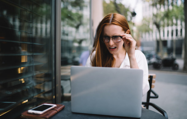 年轻女子困惑地看着笔记本电脑屏幕图片下载