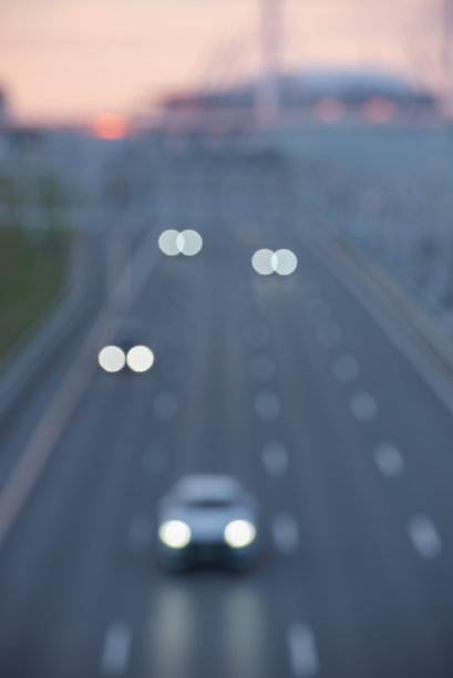 离焦的夜间公路交通和城市轮廓。垂直图片下载