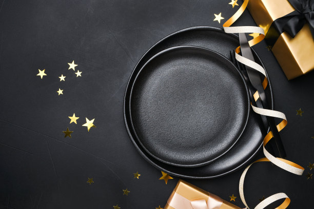 圣诞餐桌设置黑色盘子和黑色背景上的金色装饰图片下载